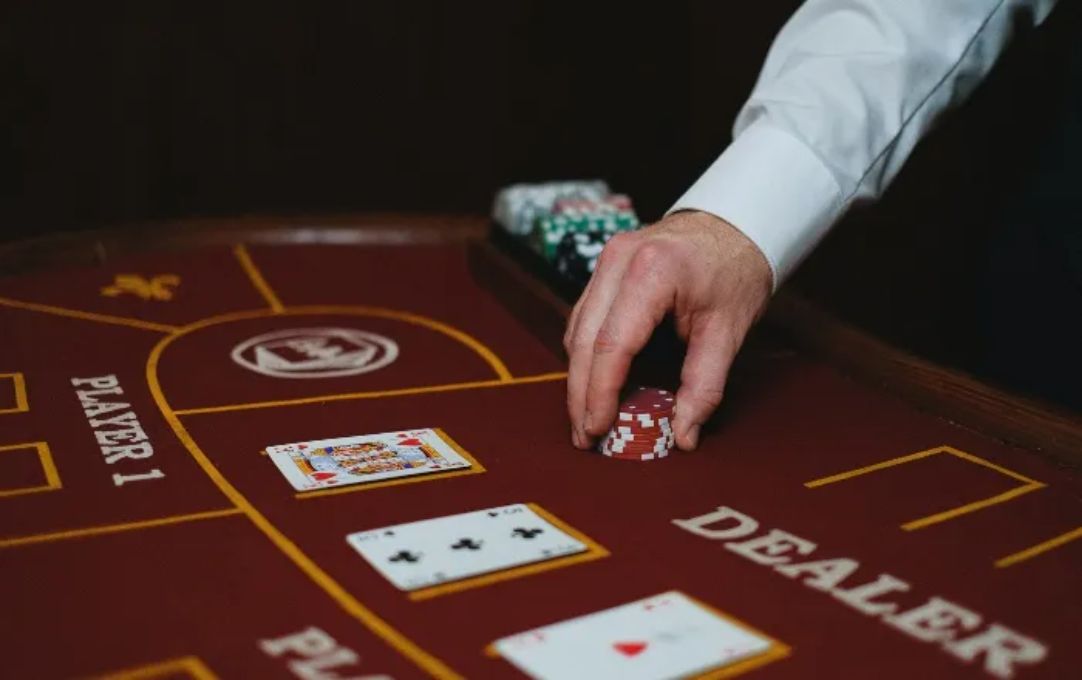 Casino dealer's hand holding chips in Maroon baccarat table